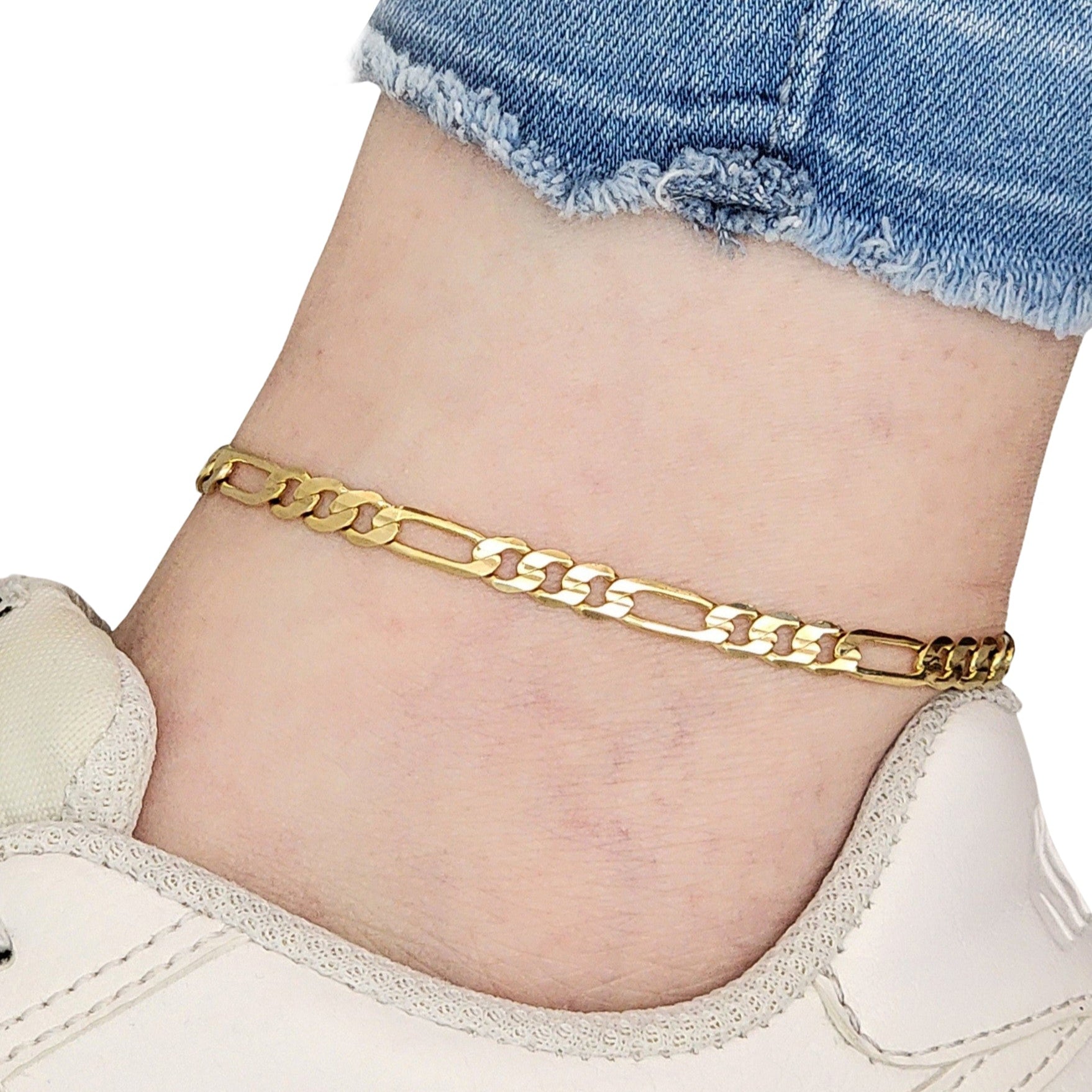 Gold Figaro chain anklet on a person's ankle with denim shorts and white sneakers.