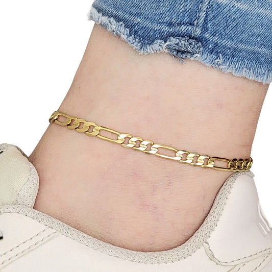Gold Figaro chain anklet on a person's ankle with denim shorts and white sneakers.