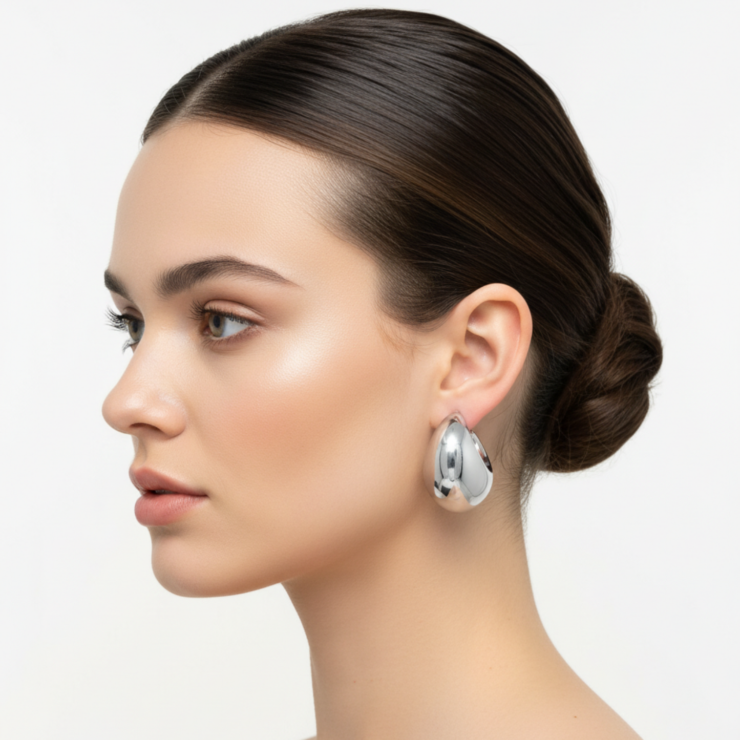 Woman wearing silver earrings with a neutral background