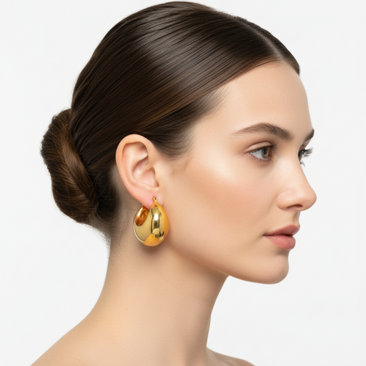 Woman wearing gold hoop earrings with a plain background