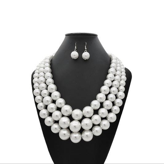 Pearl necklace and earrings set on a black mannequin bust against a white background