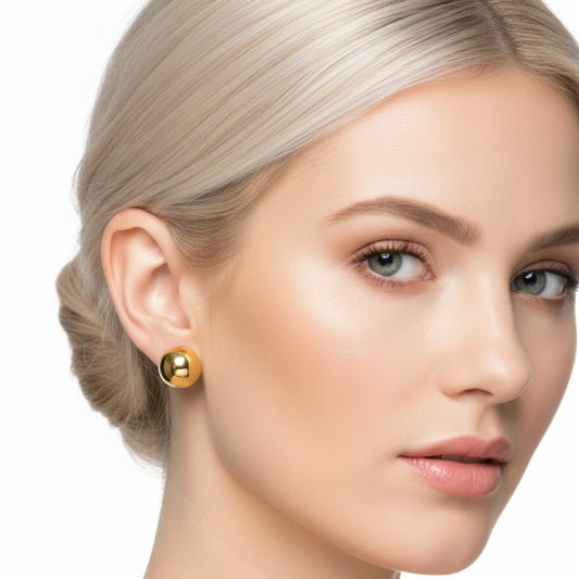 Close-up of a woman wearing gold earrings with a plain background