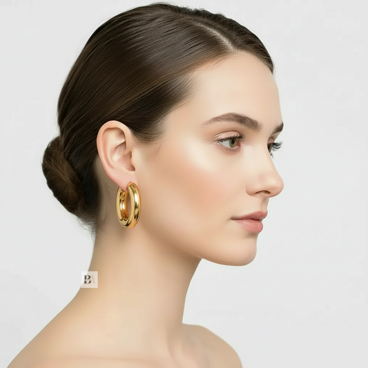 Woman wearing gold hoop earrings with a plain background