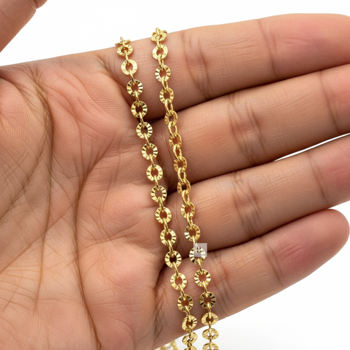 Gold chain held in a hand with a white background