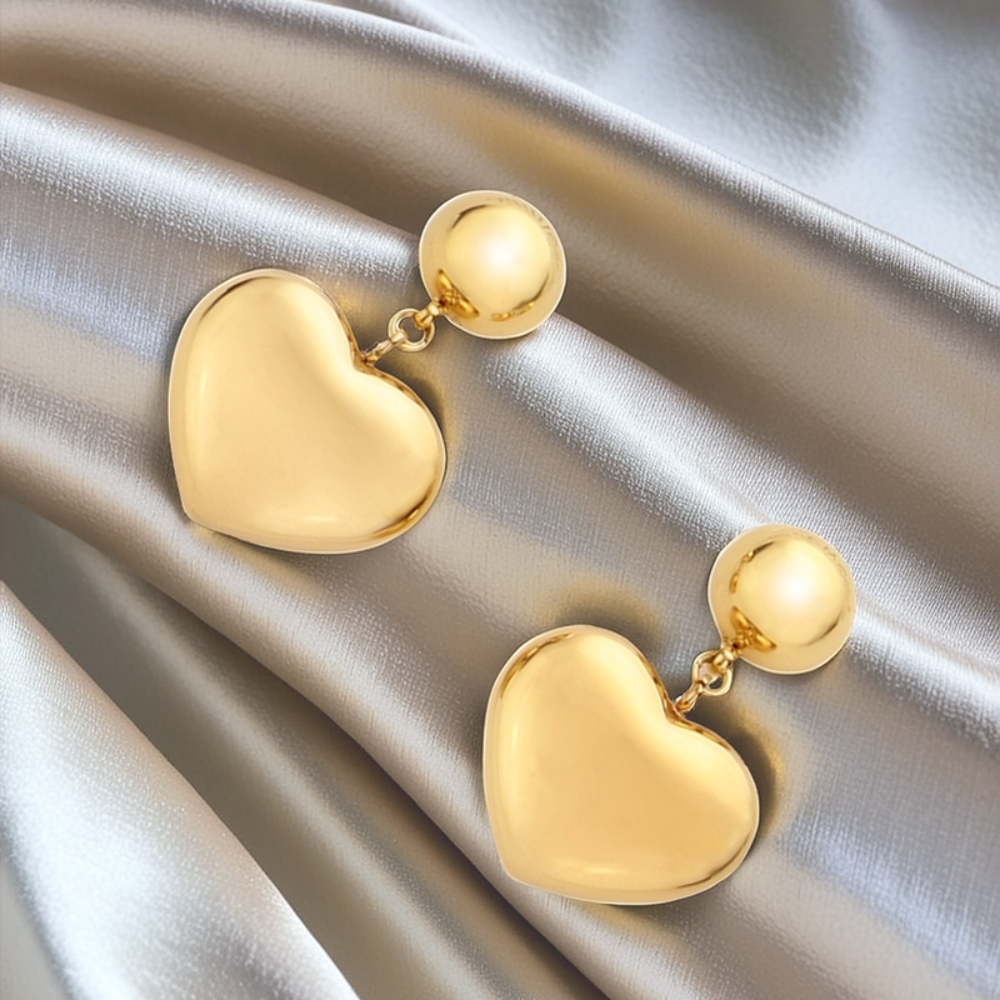 Gold heart-shaped earrings on a satin surface