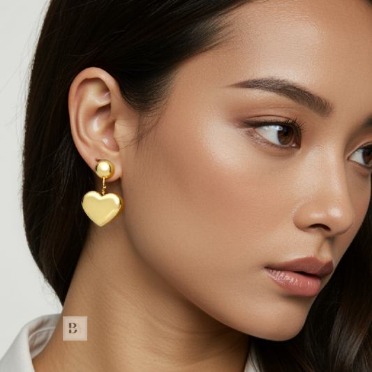 Close-up of a woman wearing gold heart-shaped earrings with a plain background
