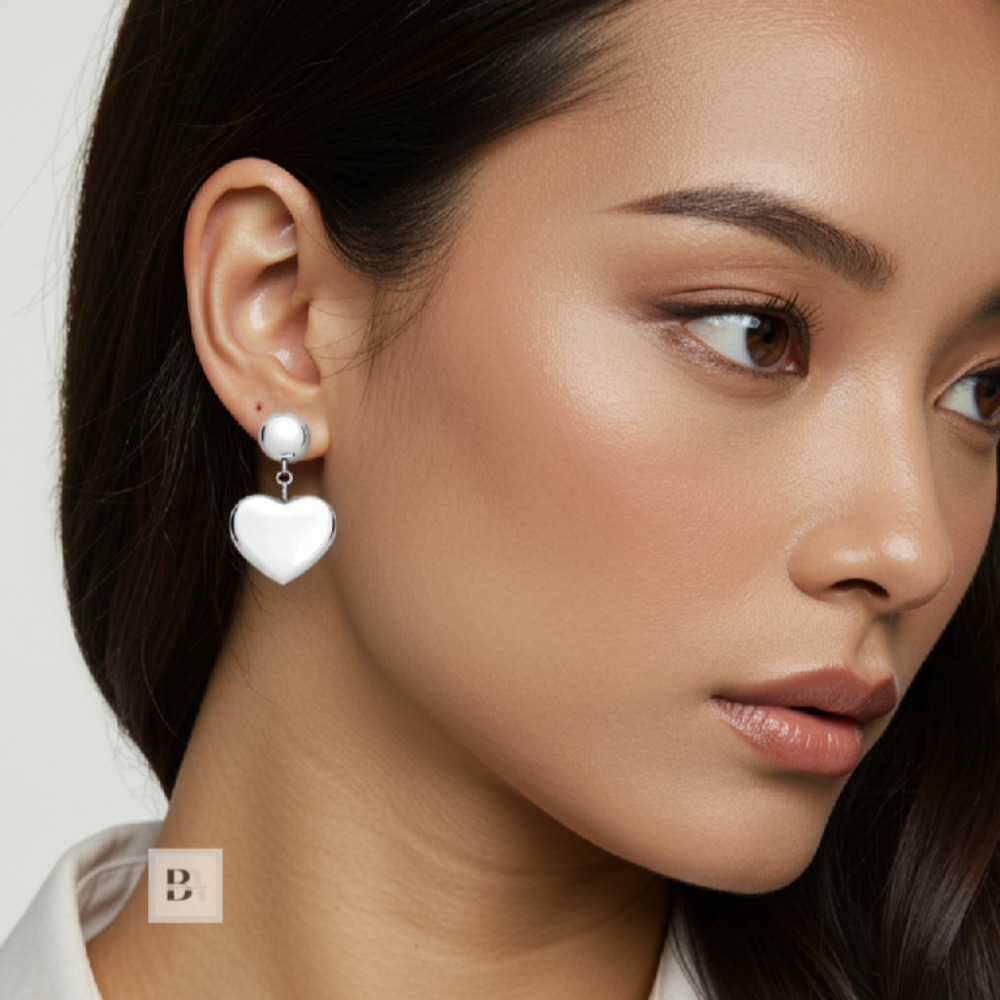 Close-up of a woman wearing heart-shaped earrings with a plain background