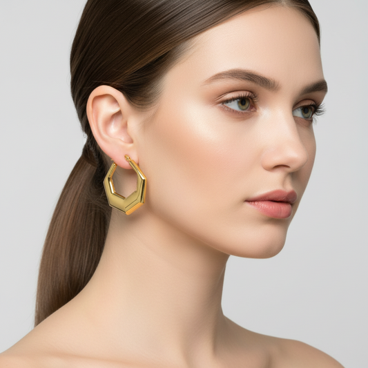 Woman wearing a gold hexagonal earring against a neutral background