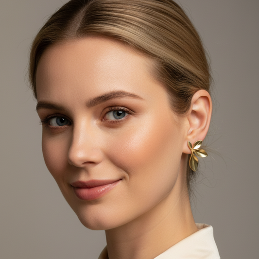 Woman wearing gold earrings with a neutral background