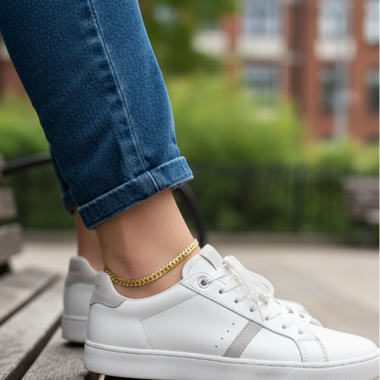 White sneakers worn with blue jeans on a wooden bench outdoors.