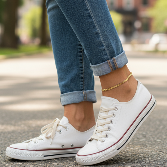 White sneakers with red accents worn with rolled-up jeans on a street.
