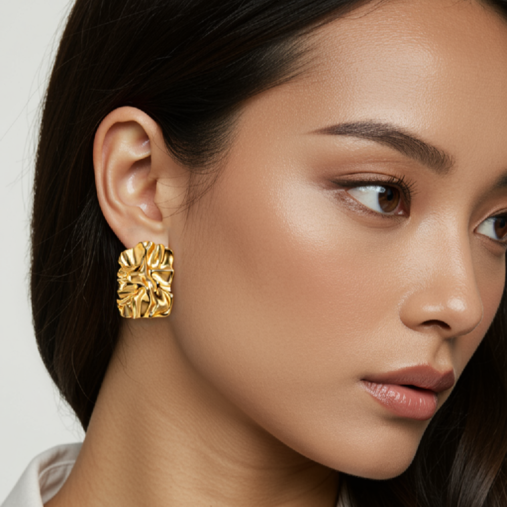 Woman wearing gold earrings with a plain background