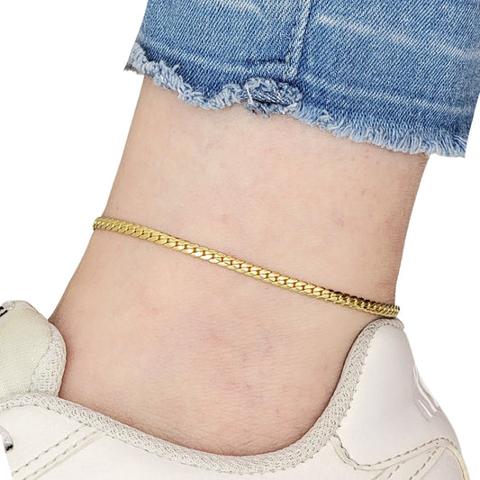 Gold Miami Cuban chain anklet on a person's ankle with denim shorts and white sneakers.