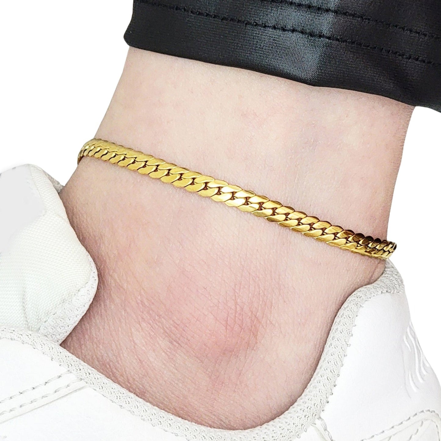 Gold anklet on a person's ankle with a white background