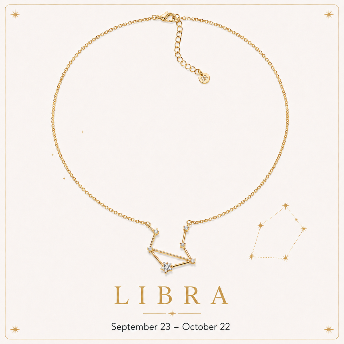 A gold-tone Libra necklace with a constellation pendant and a small clear central stone, displayed on a cream background with the word LIBRA and the date range September 23 – October 22.