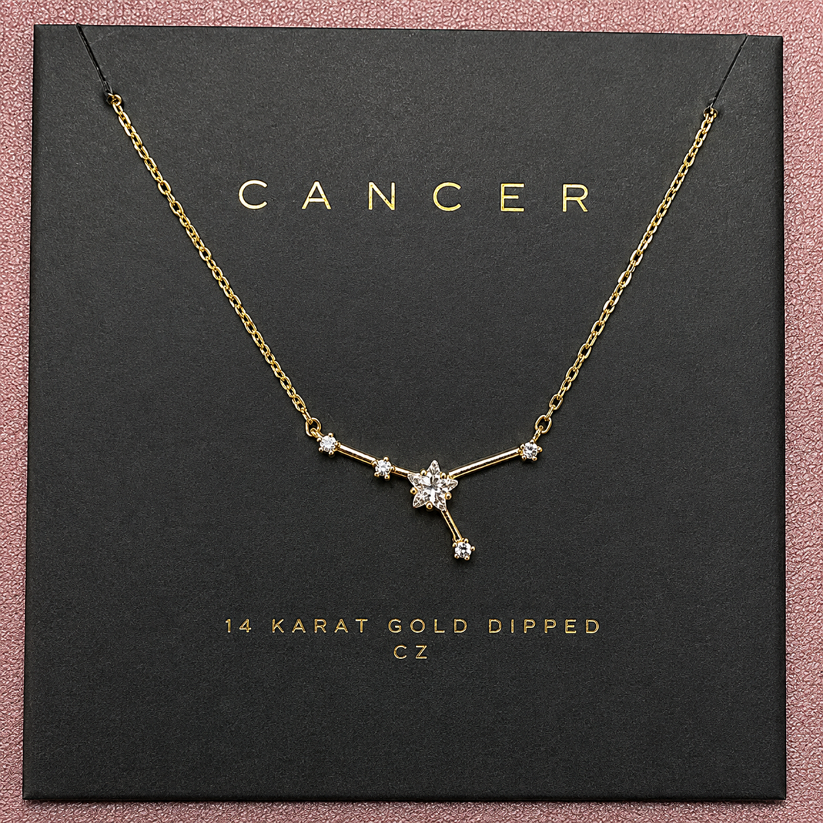 A gold necklace with a star and branch pendant displayed on a black jewelry card labeled 'CANCER' and '14 KARAT GOLD DIPPED CZ'.