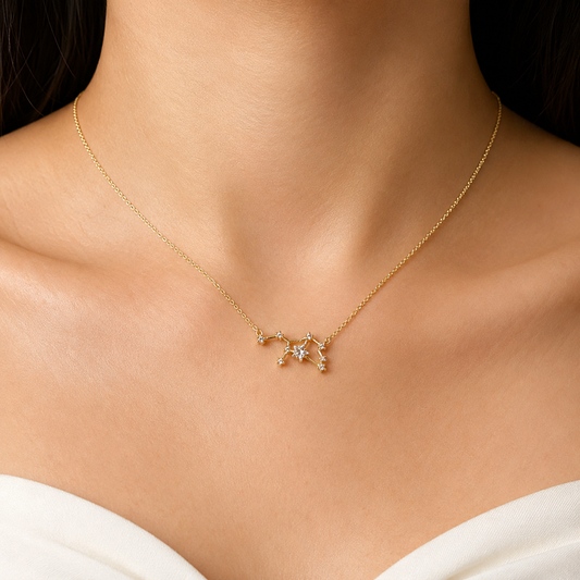 A delicate gold chain necklace with a small star and crescent moon pendant, worn on a model's neck above a white strap.