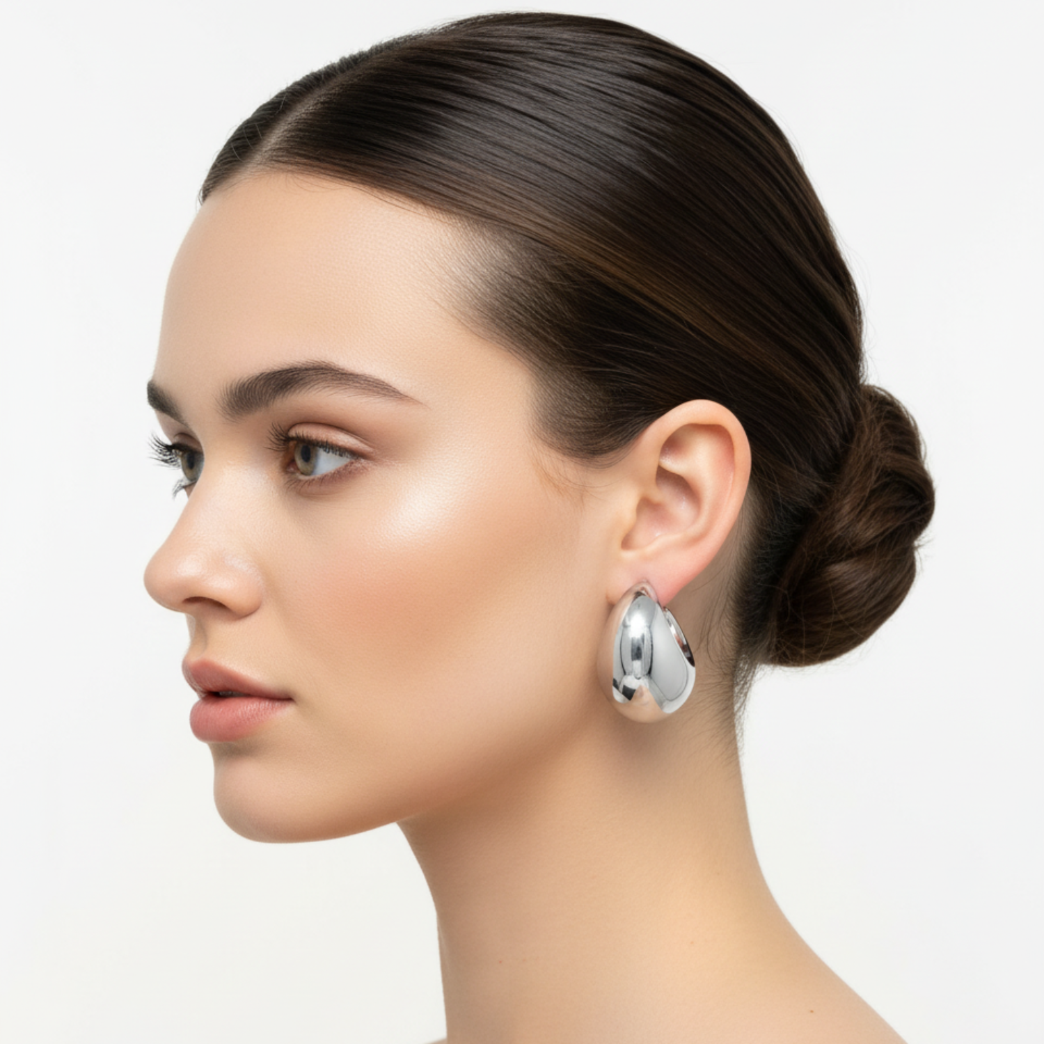 Woman wearing silver earrings with a neutral background
