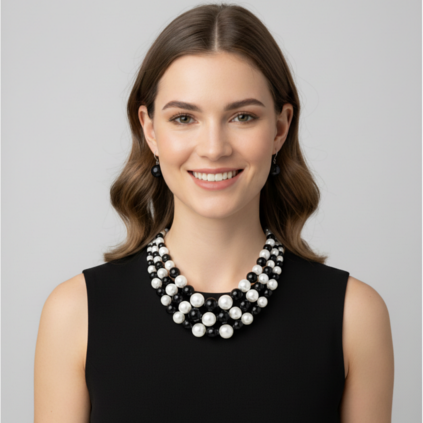 Woman wearing a black and white beaded necklace against a gray background