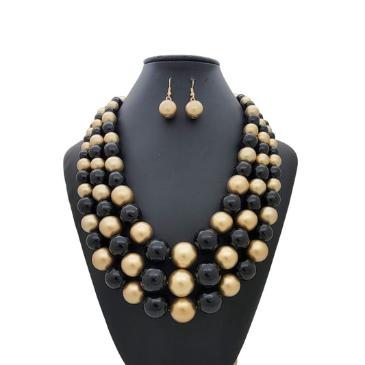 Black and gold beaded necklace and earrings set on a black mannequin bust.