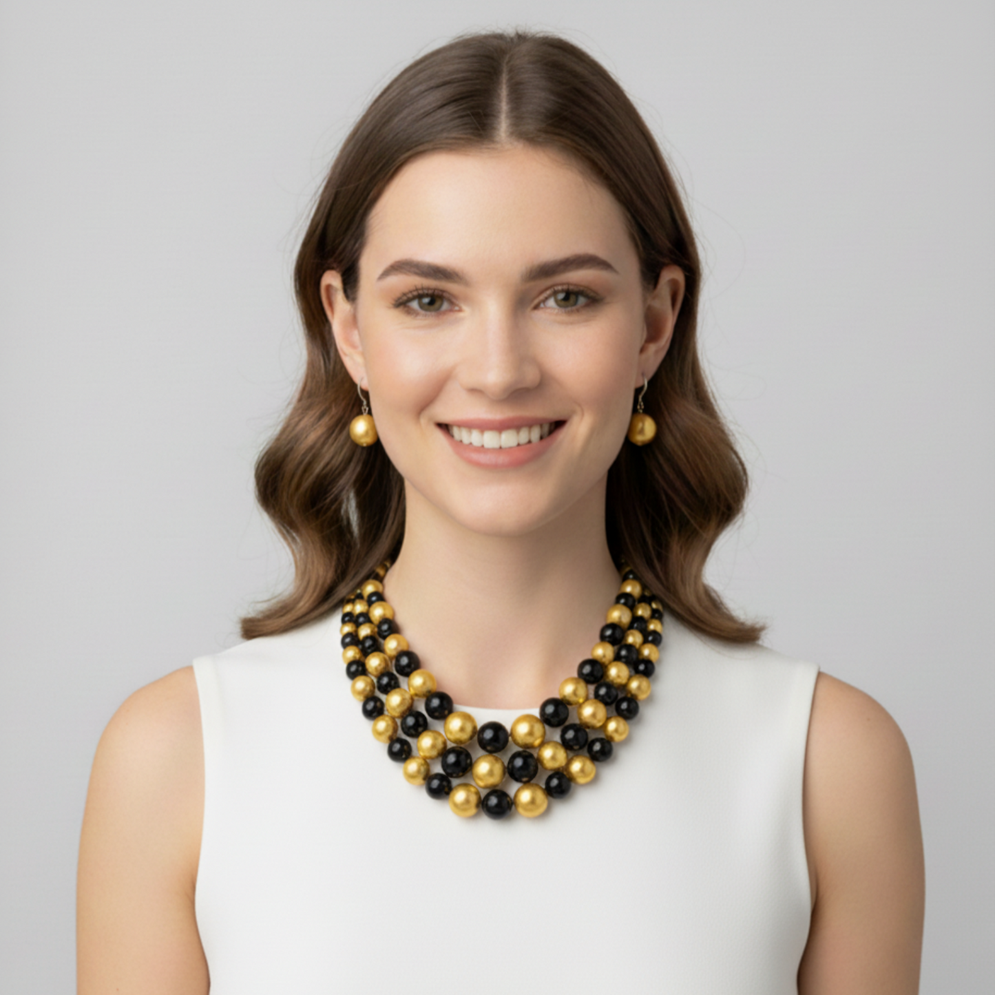 Woman wearing a black and gold beaded necklace against a gray background