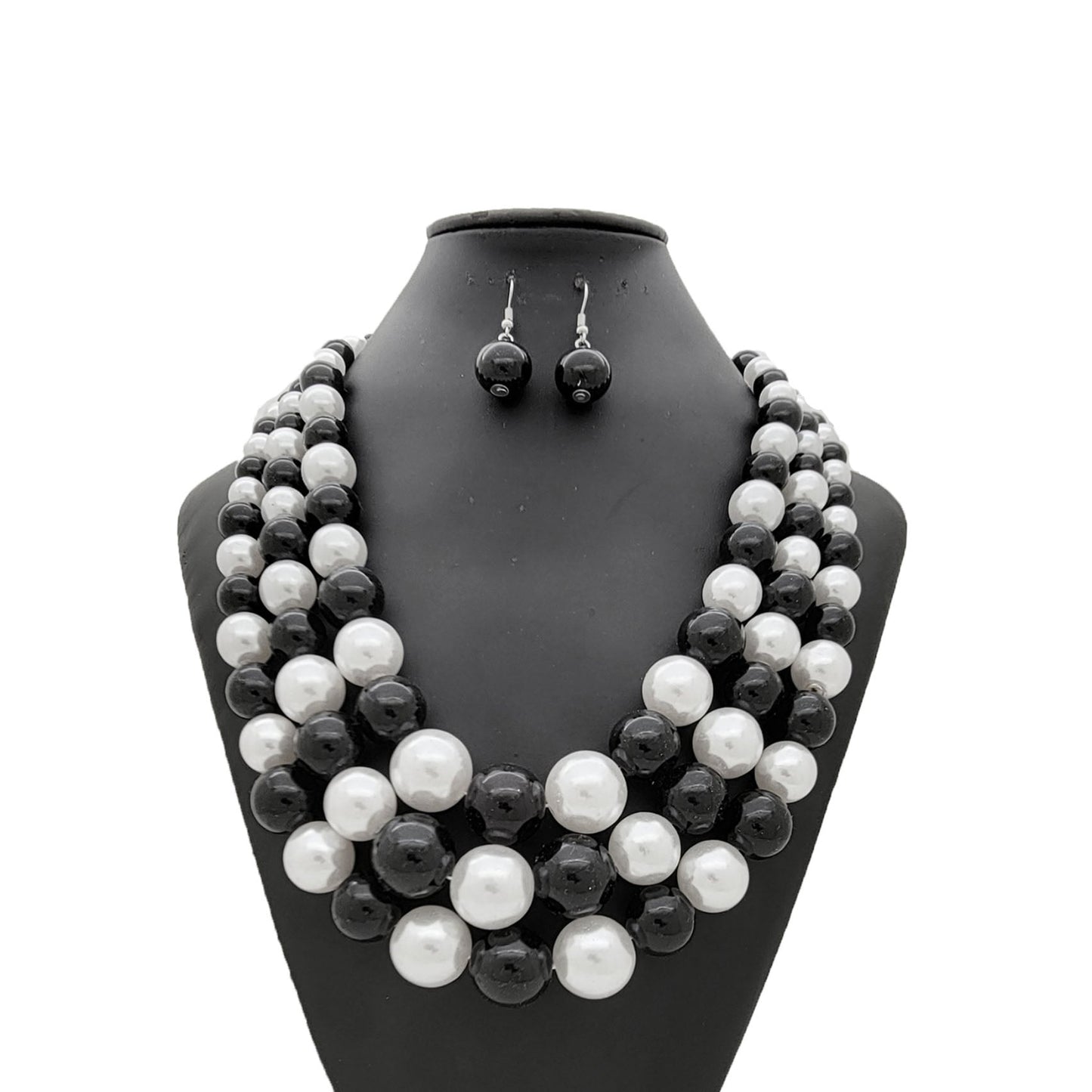 Black and white pearl necklace and earrings set on a black mannequin bust.