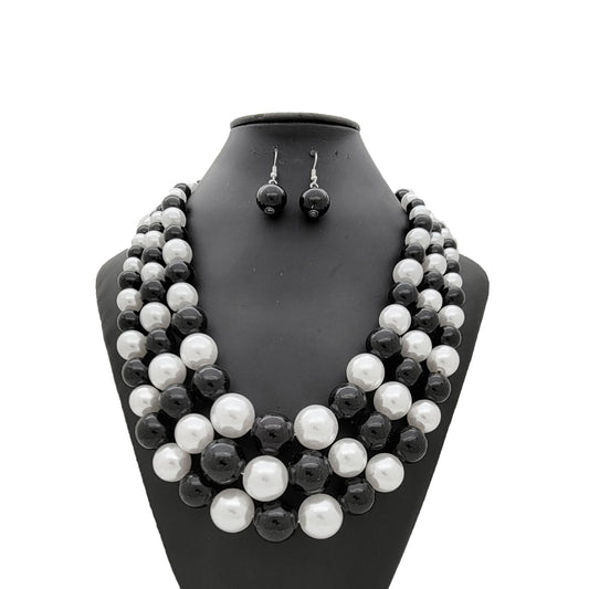 Black and white pearl necklace and earrings set on a black mannequin bust.