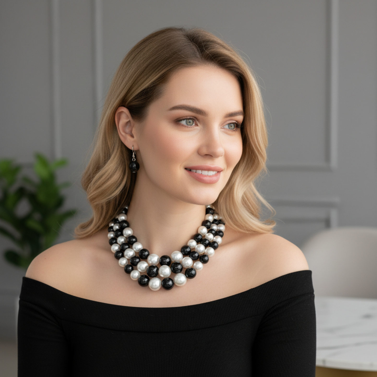 Woman wearing a black and white pearl necklace against a neutral background