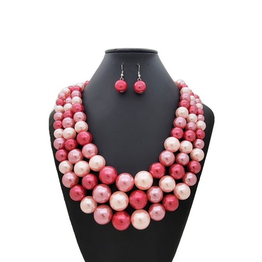 Pink and white pearl necklace and earrings on a black mannequin bust.