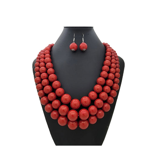 Red beaded necklace and earrings set on a black mannequin bust against a white background