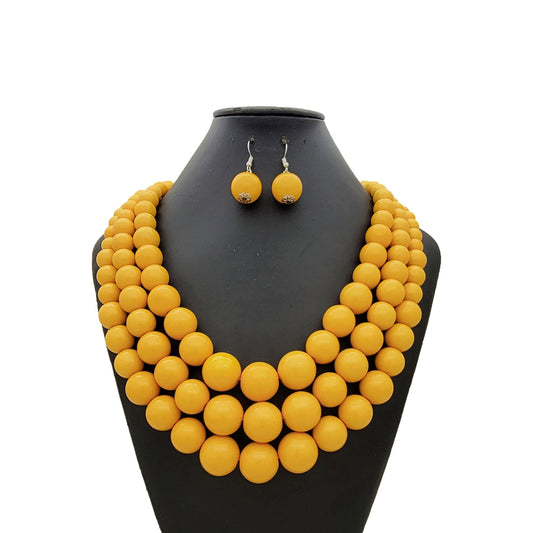 Yellow necklace and earrings set on a black mannequin bust against a white background