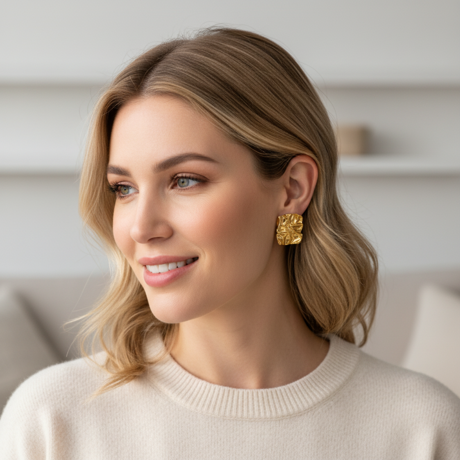 Woman wearing gold earrings in a neutral setting