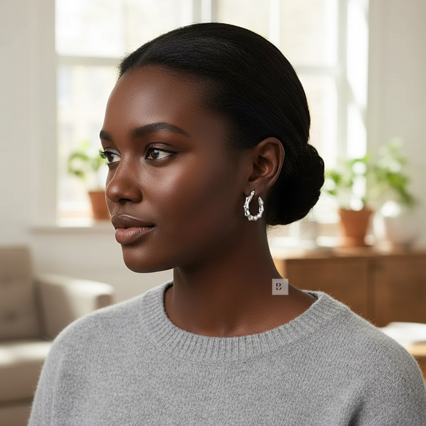 Woman wearing hoop earrings in a bright room with plants