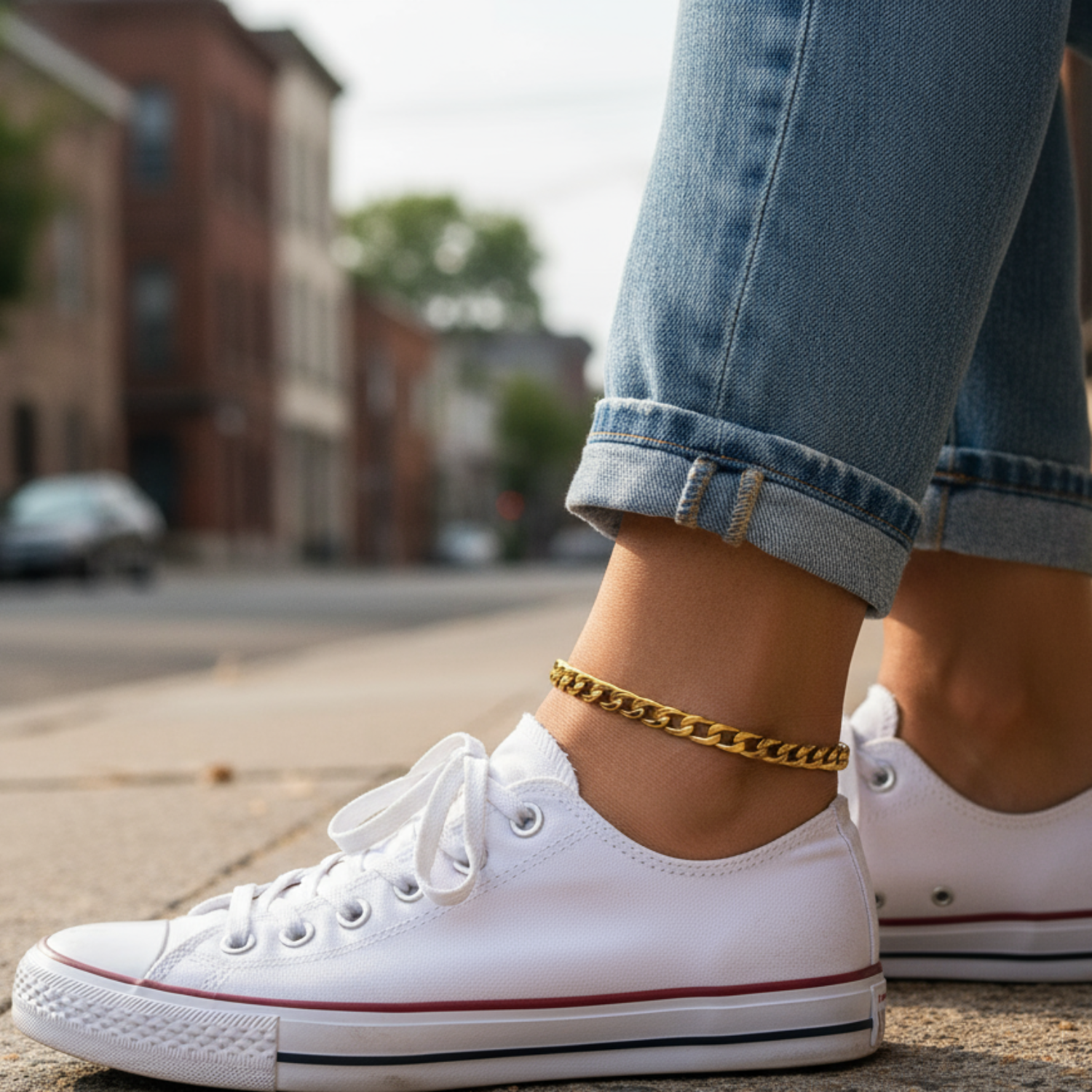 White sneakers with red accents worn on a street, with jeans rolled up.