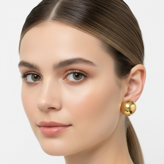Woman wearing gold earrings against a white background