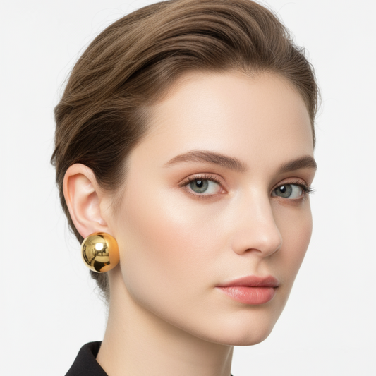 Woman wearing gold earrings with a plain background