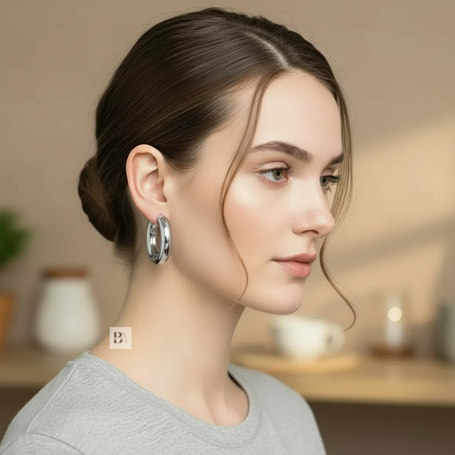 Woman wearing silver hoop earrings with a blurred indoor background