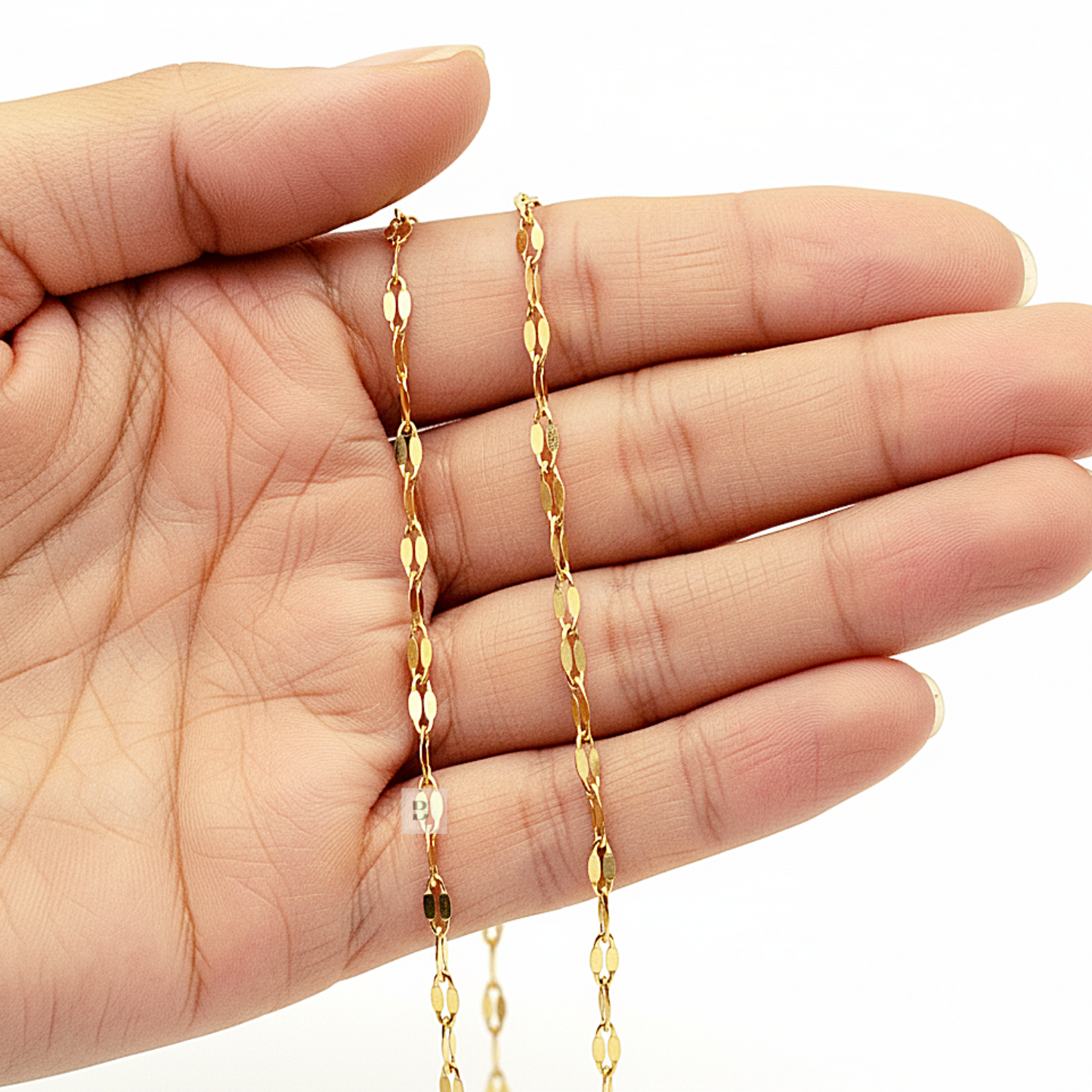 Gold Ankle chain held in a hand against a white background