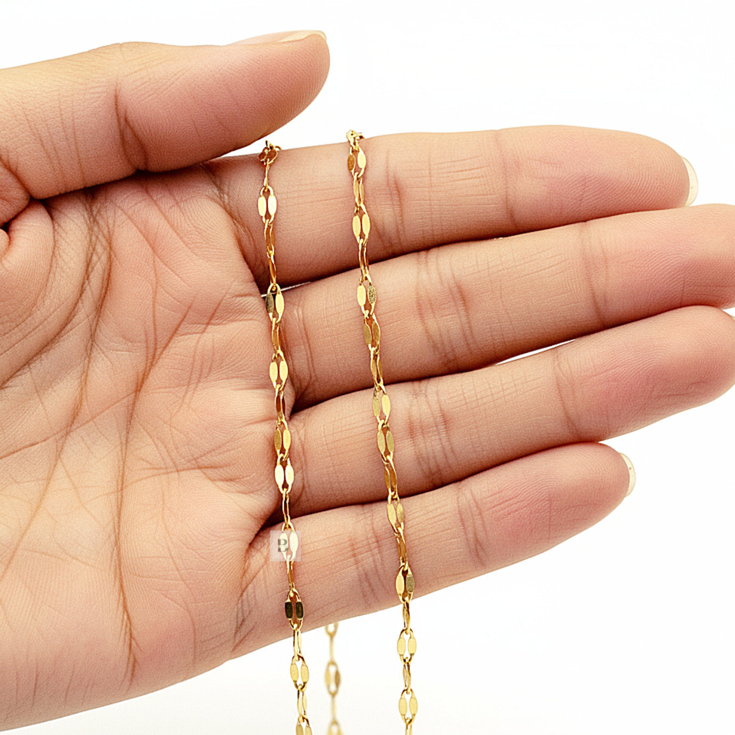Gold Ankle chain held in a hand against a white background