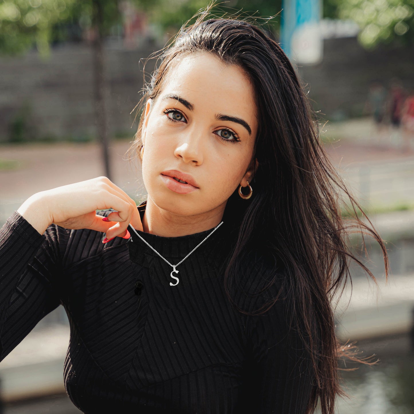 Woman wearing a black ribbed sweater with a 'S' necklace 