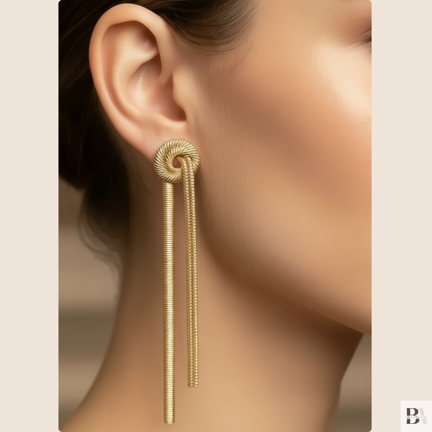 Gold earring worn by a model on a beige background