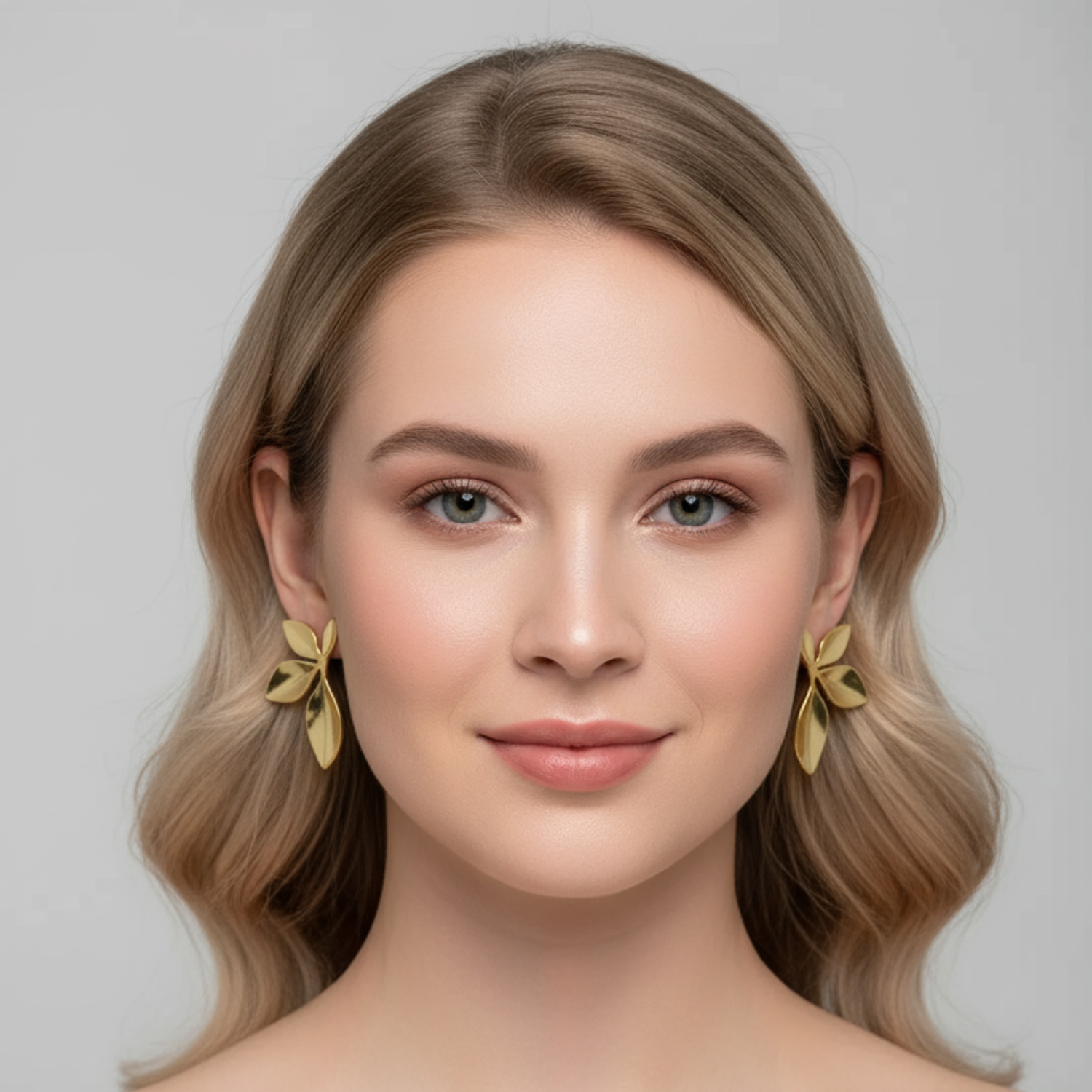 Woman with styled hair and gold bow earrings against a neutral background