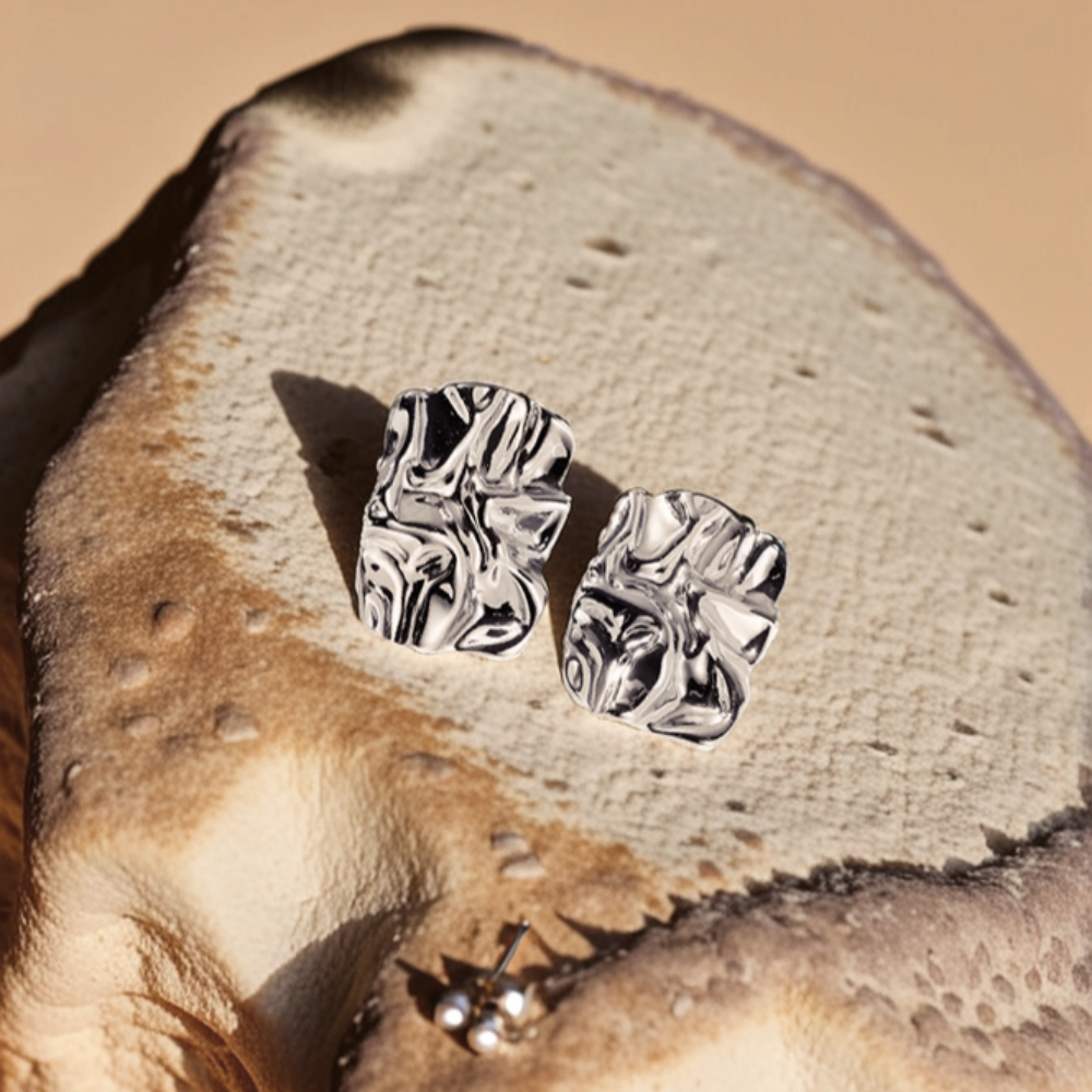 Silver earrings on a textured stone surface