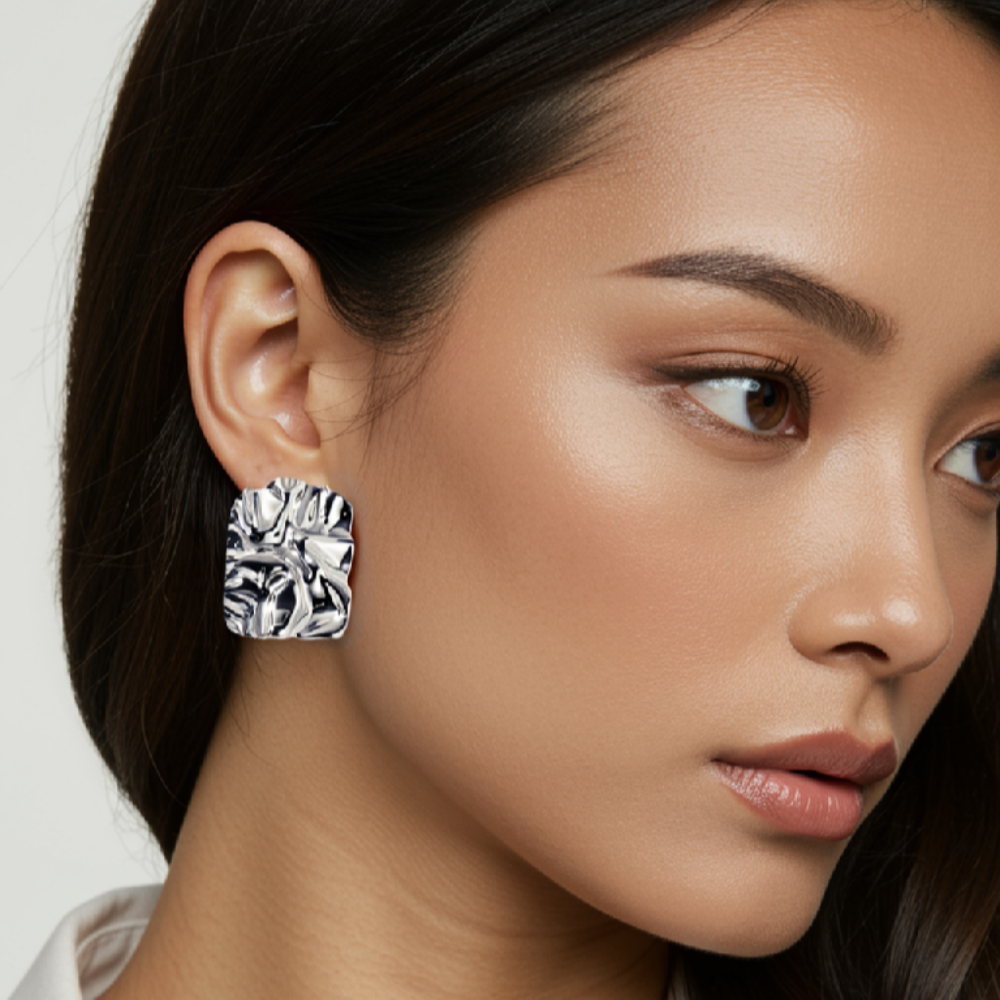 Close-up of a woman wearing a large diamond earring with a plain background