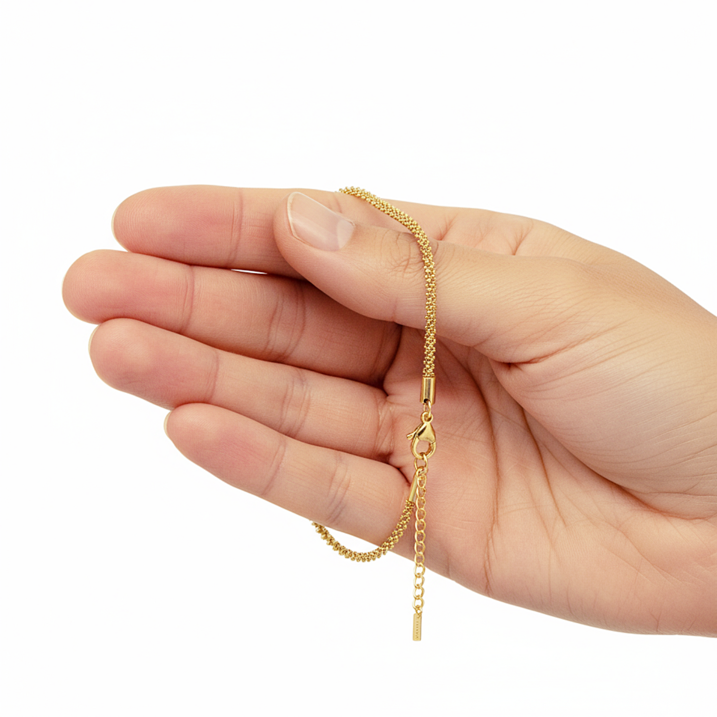Gold chain held in a hand on a white background