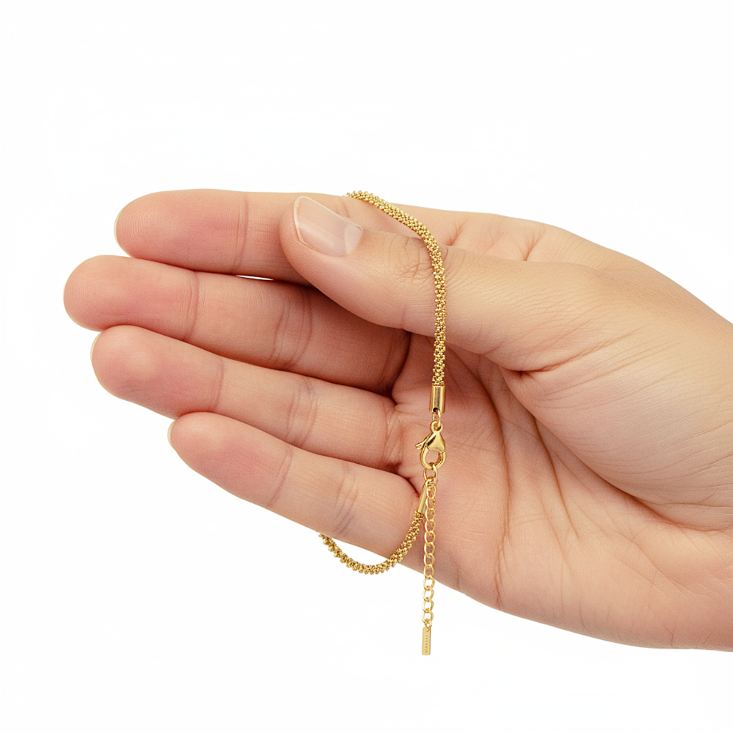 Gold chain held in a hand on a white background